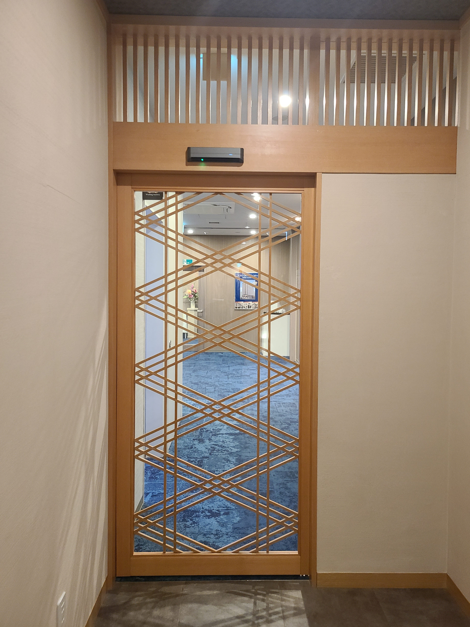 The automatic door featuring traditional Japanese woodwork leads to the public bath hallway 