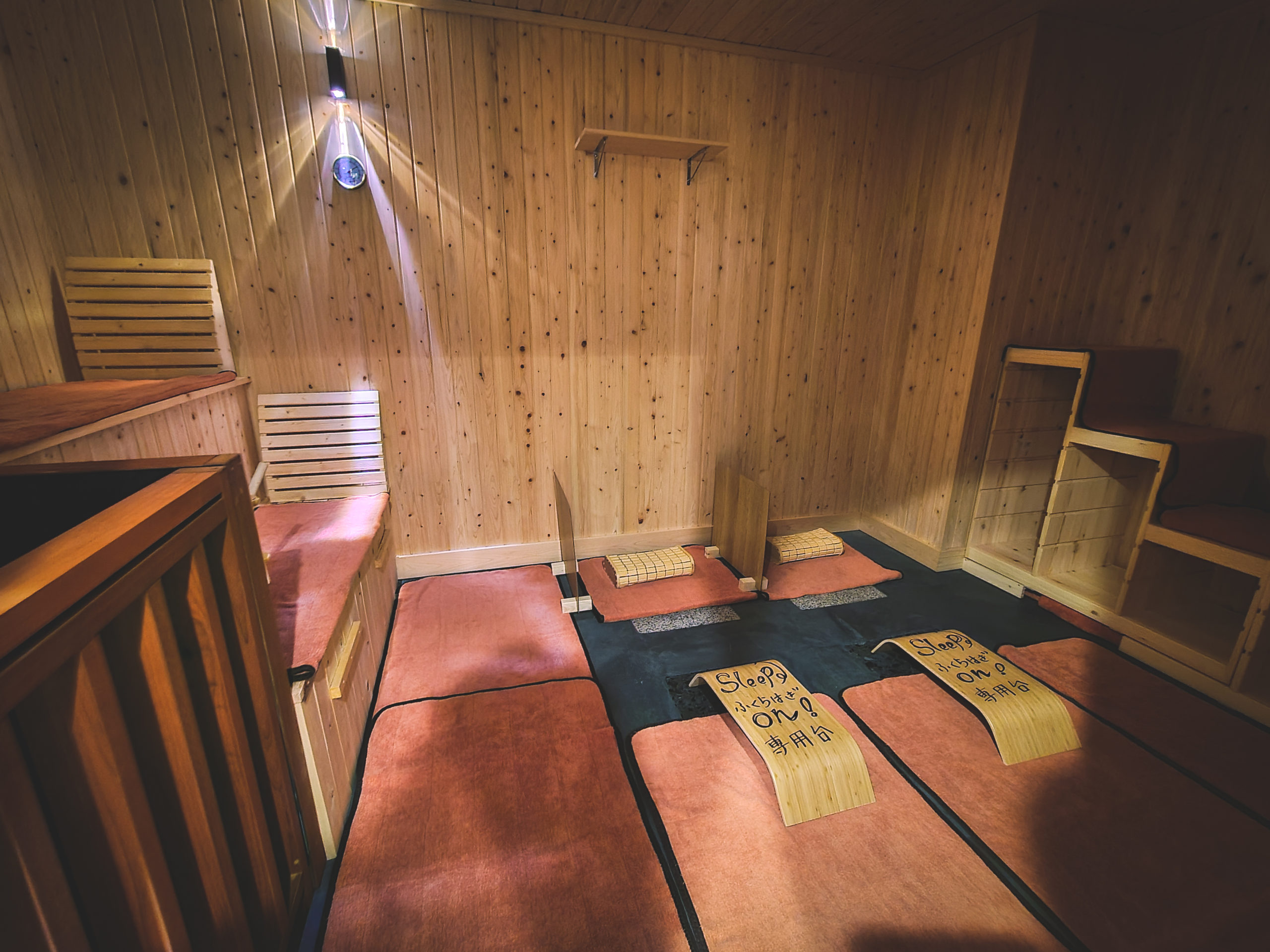 The sauna room floor features a ganbanyoku—a stone sauna using natural heated rock and has areas for sitting as well as laying down